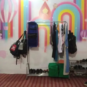 Clothing rack with bags and clothes against a colorful wall.
