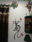 Decorative wall with floral arrangements and a wall decal of a plant and butterflies.