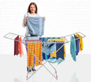 Woman holding a towel with a drying rack full of clothes on a white background