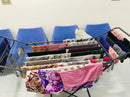 Folded clothes on a metal rack against a white wall with blue chairs.