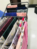 Clothing rack with folded clothes on a white floor