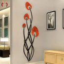 Decorative wall art with orange flowers and black branches on a wall in a room.