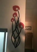Decorative wall art with red flowers and black stems on a white wall.