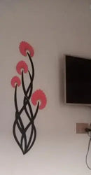Decorative wall art with pink flowers and black vines on a white wall next to a television.