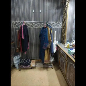 Clothing rack with clothes in a room with a mirror and desk.