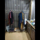 Clothing rack with clothes in a room with a mirror and desk.
