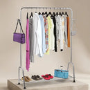 Clothing rack with clothes, shoes, and bags on a neutral background