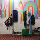 Clothing rack with bags and clothes against a colorful wall.