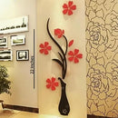 Decorative wall art with a black vase and red flowers on a beige wall.