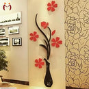 Decorative wall art with a black vase and red flowers on a beige wall.