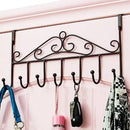 Decorative wall-mounted hook rack with various items hanging on it against a pink background
