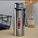 Stainless steel thermos bottle with a label on a table with a neutral background