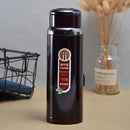 Black thermos bottle with a label on a wooden surface with a blurred background